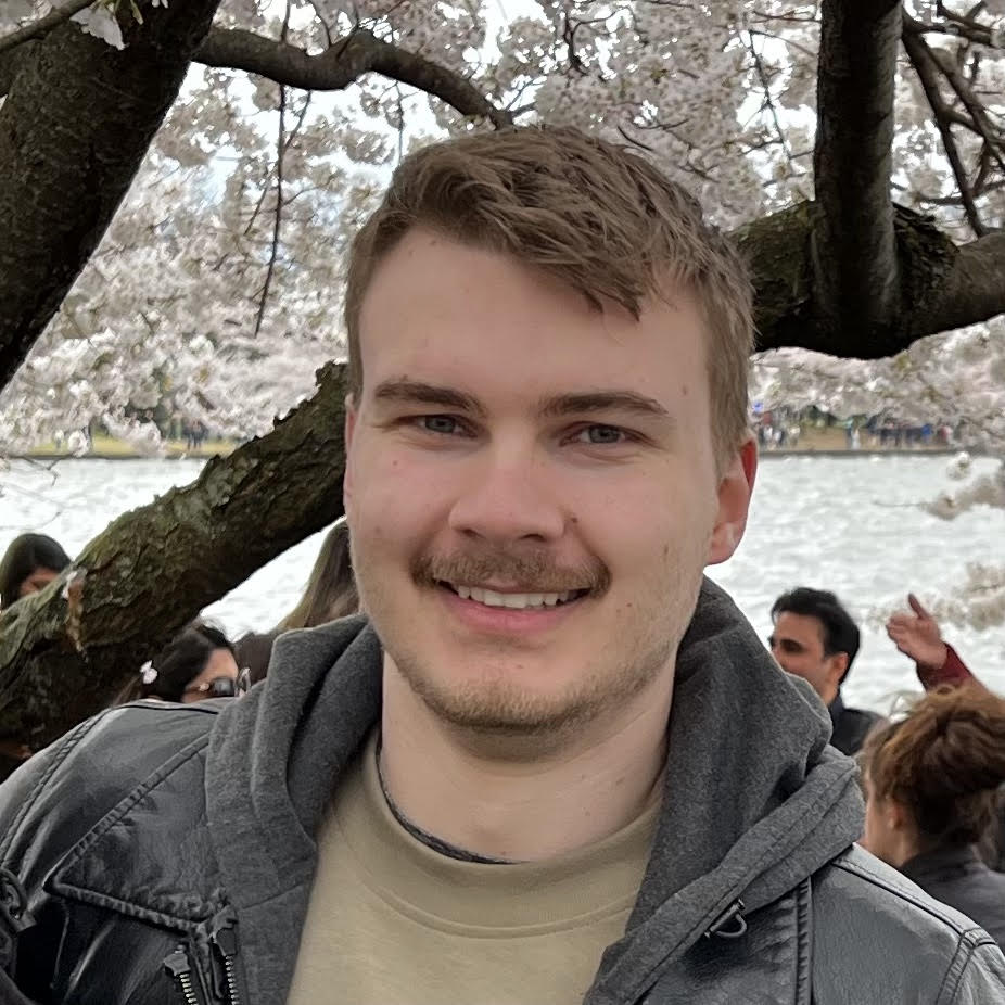Image of graduate student Ben Kass in front of a cherry blossom tree at the Tidal Basin