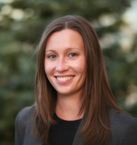 Professional headshot against a blurred foilage background