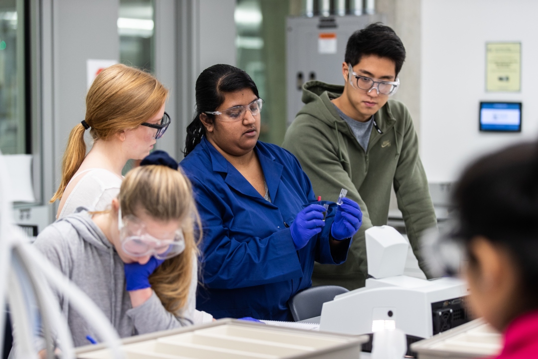 4 GW chemistry students looking at a test tube