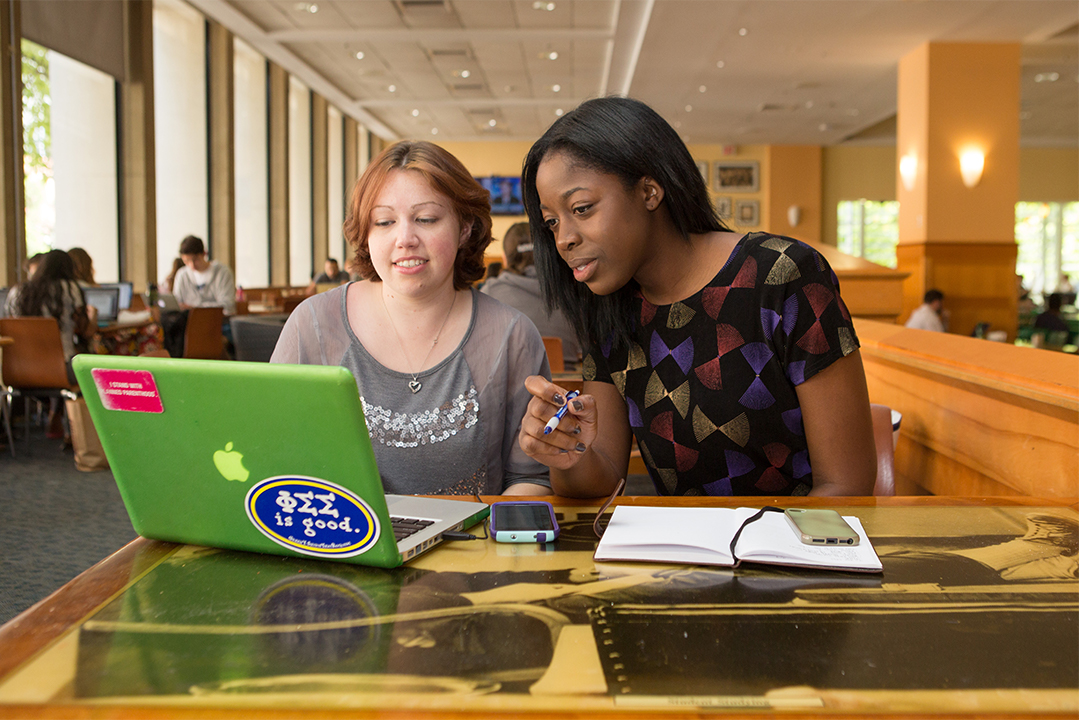 2 CCAS students looking at a computer