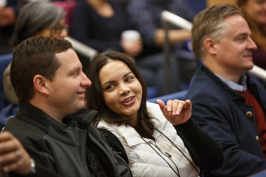 Two students in the audience of an event talking to each other