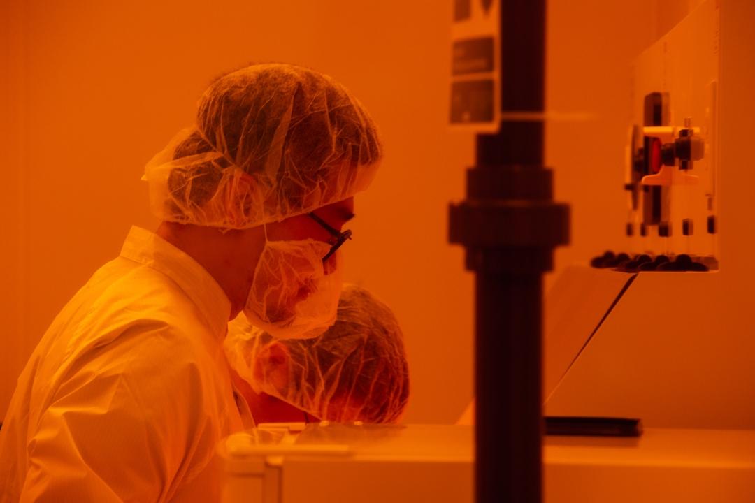 GW chemist in an orange-lit lab wearing a mask and white coat