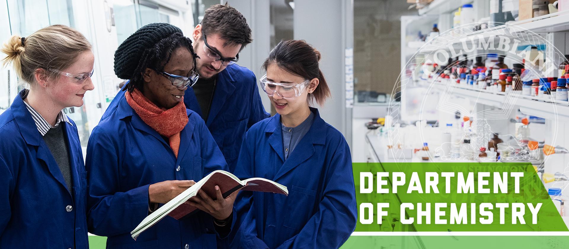 Graduate Students in a lab looking at lab book