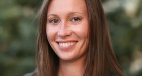 Professional headshot against a blurred foilage background